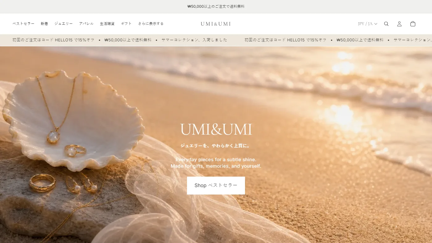 The UMI&UMI homepage in Japanese: gold jewellery resting on a shell at the water's edge.